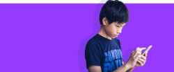 Young boy focusing on his phone with a purple background